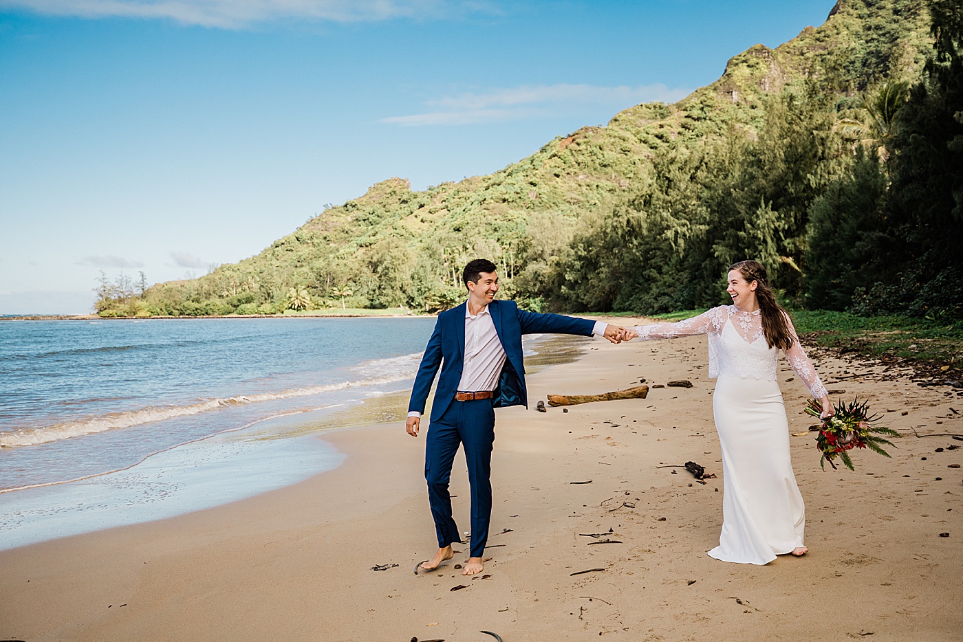 Adventurous Oahu elopement at the beach. Bride and groom holding hands running down the beach.